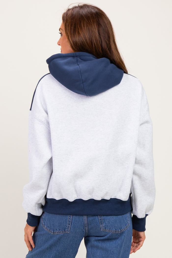 woman wearing a gray and navy hoodie with a cropped fit and ribbed cuffs, seen from the back