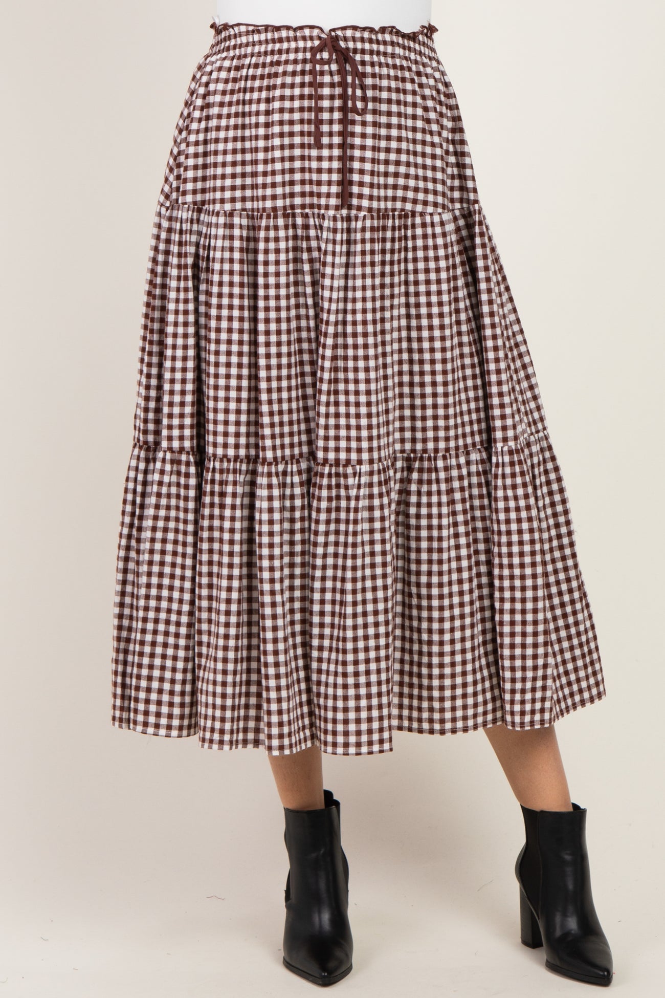 woman wearing a brown and white gingham tiered midi skirt with an elastic waist and drawstring detail