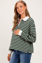 woman wearing a green and white striped maternity pullover with a collar and holding her baby bump
