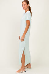 woman wearing a light mint green maxi dress with short sleeves and side slits, standing sideways