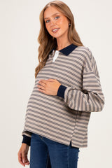 woman wearing a beige and navy striped maternity pullover with a visible baby bump and side slits, smiling at the camera