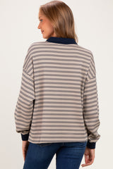 woman wearing a beige striped maternity top with navy accents and balloon sleeves, view from the back