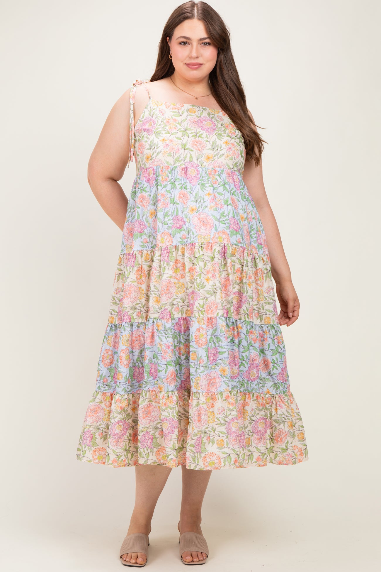 woman wearing a floral print maternity plus dress with a tiered skirt and adjustable straps