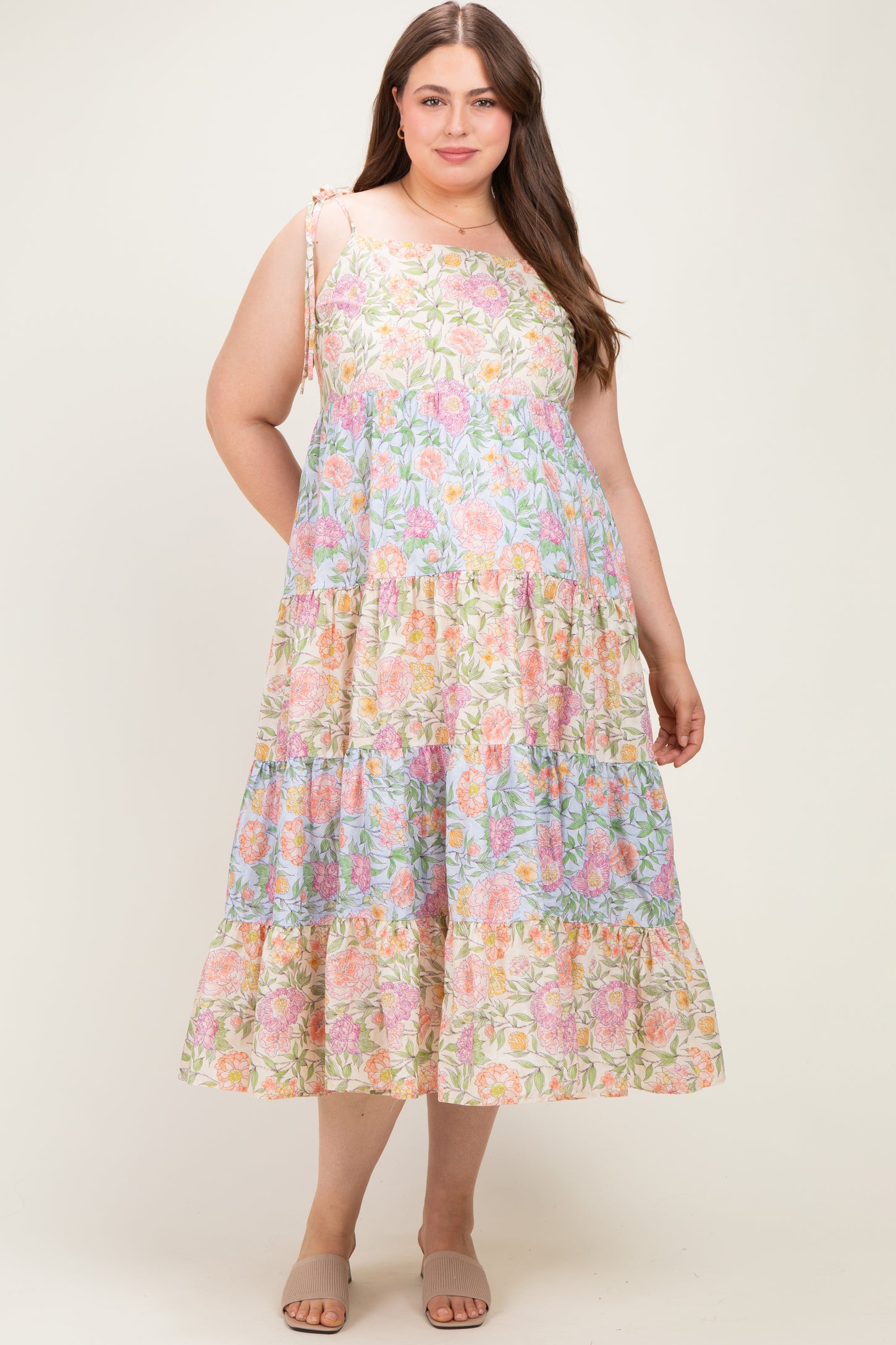woman wearing a floral print maternity plus dress with a tiered skirt and adjustable straps