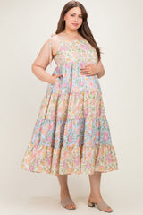 woman wearing a floral print maternity plus dress with adjustable straps and pockets, gently holding her baby bump