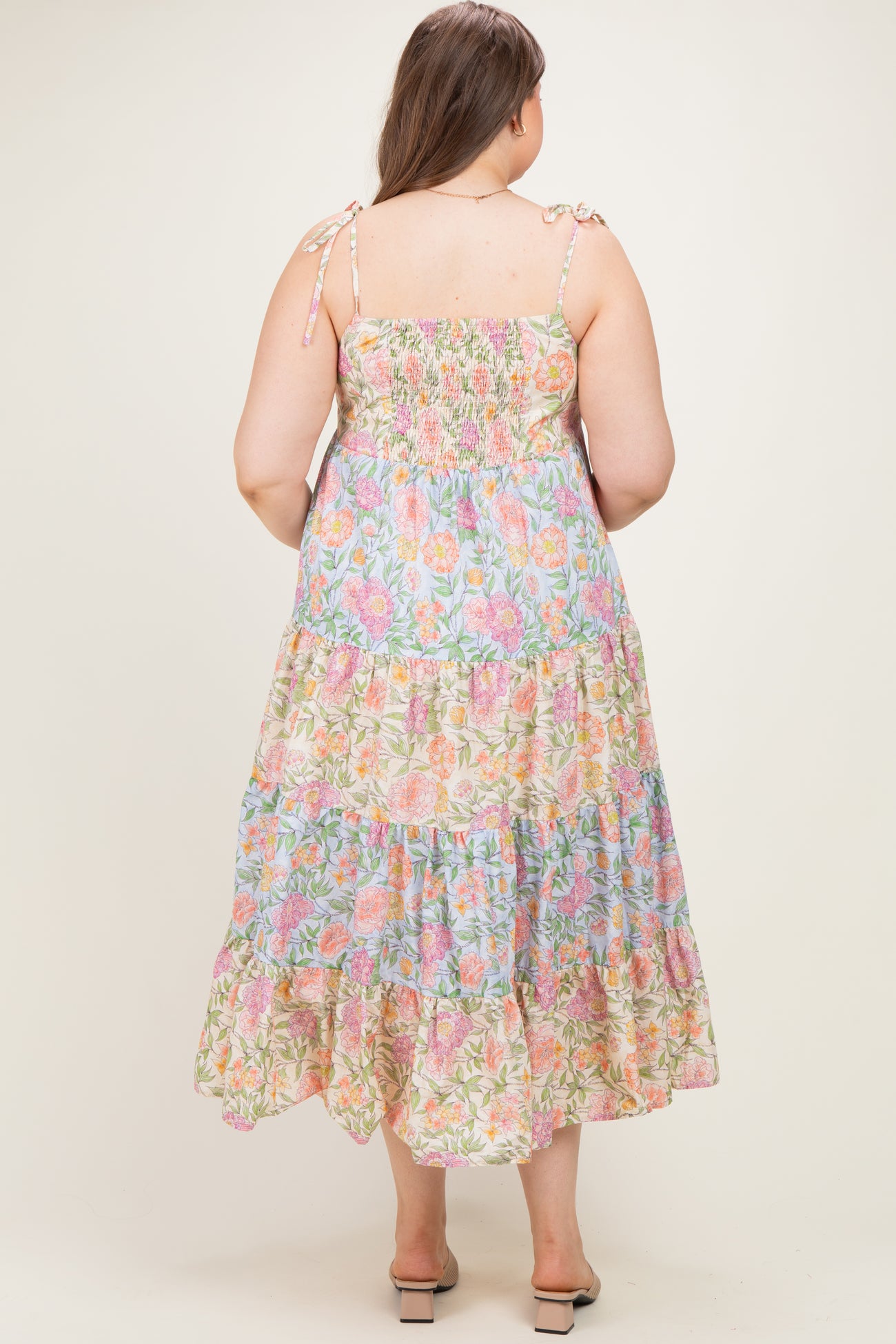 woman wearing a floral print maternity plus maxi dress with adjustable tie straps and tiered ruffles, shown from the back