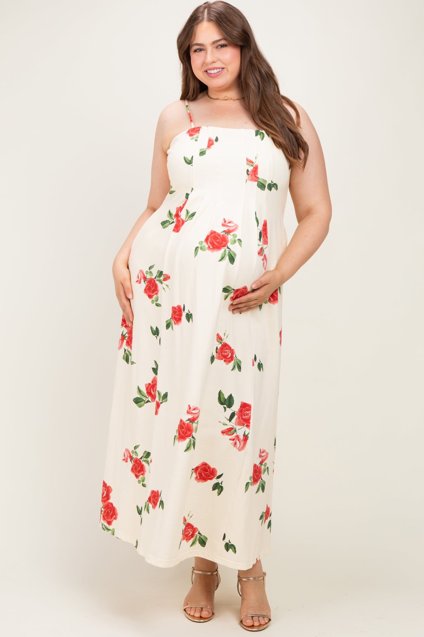 woman wearing a floral print white maternity maxi dress and holding her baby bump