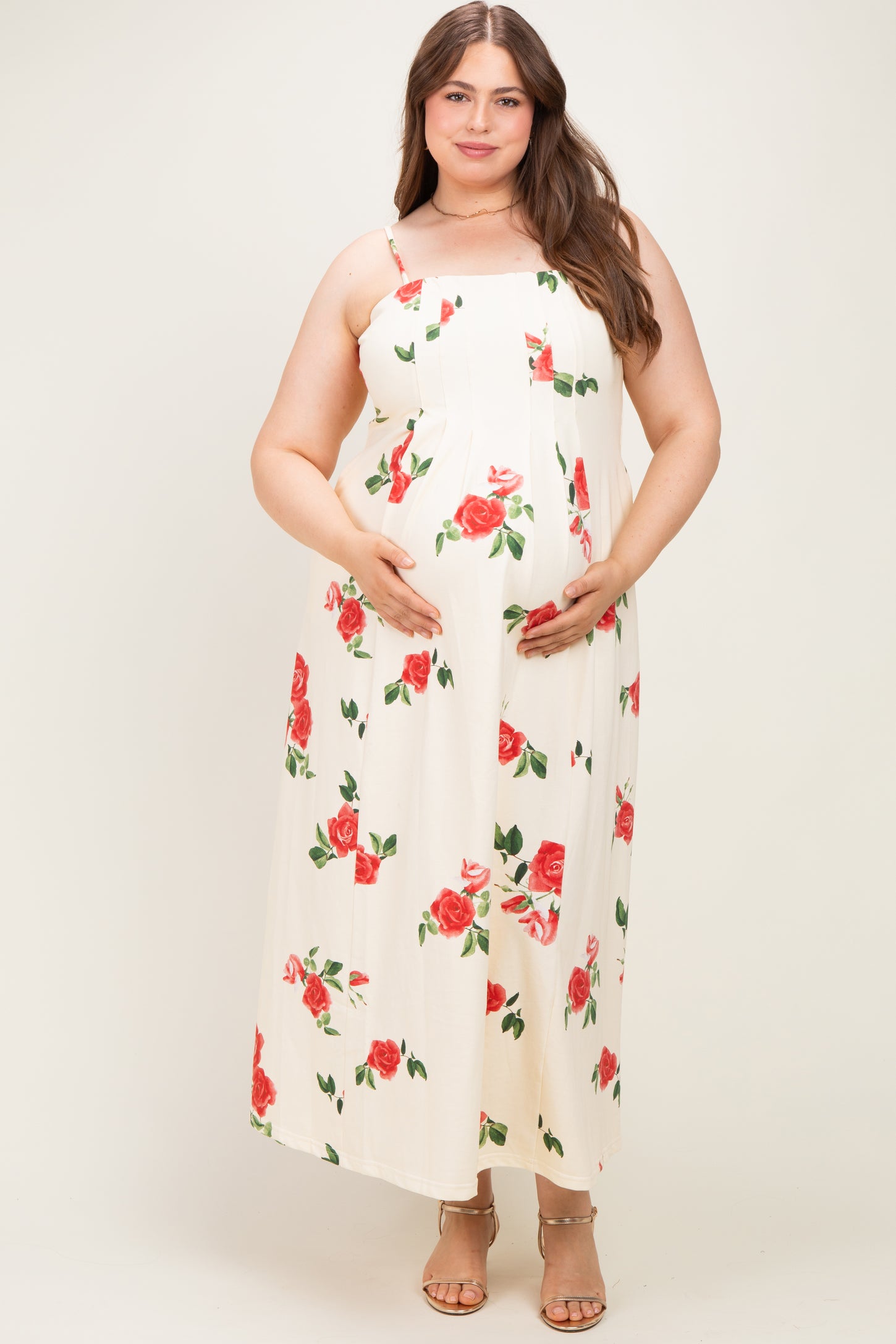 woman wearing a floral print maternity maxi dress with red roses and a visible baby bump