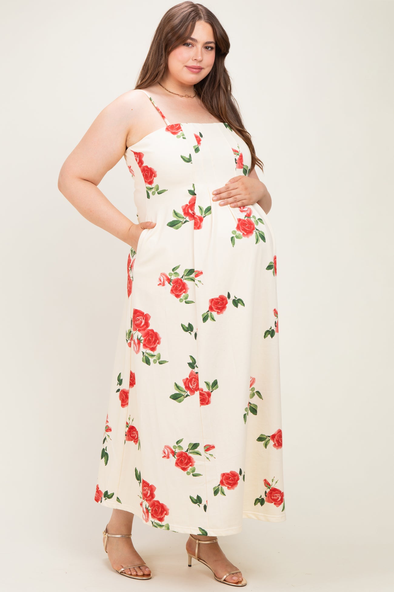 woman wearing a cream floral maternity maxi dress with pockets and a baby bump