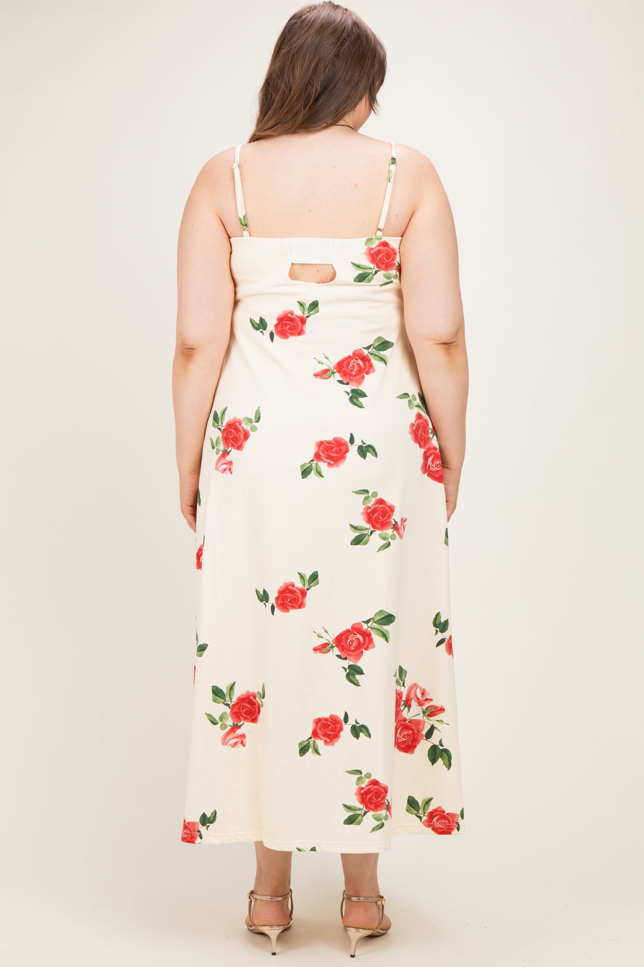 woman wearing a cream maternity plus maxi dress with a floral print and back cutout detail