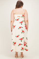 woman wearing a cream maternity plus maxi dress with a floral print and back cutout detail