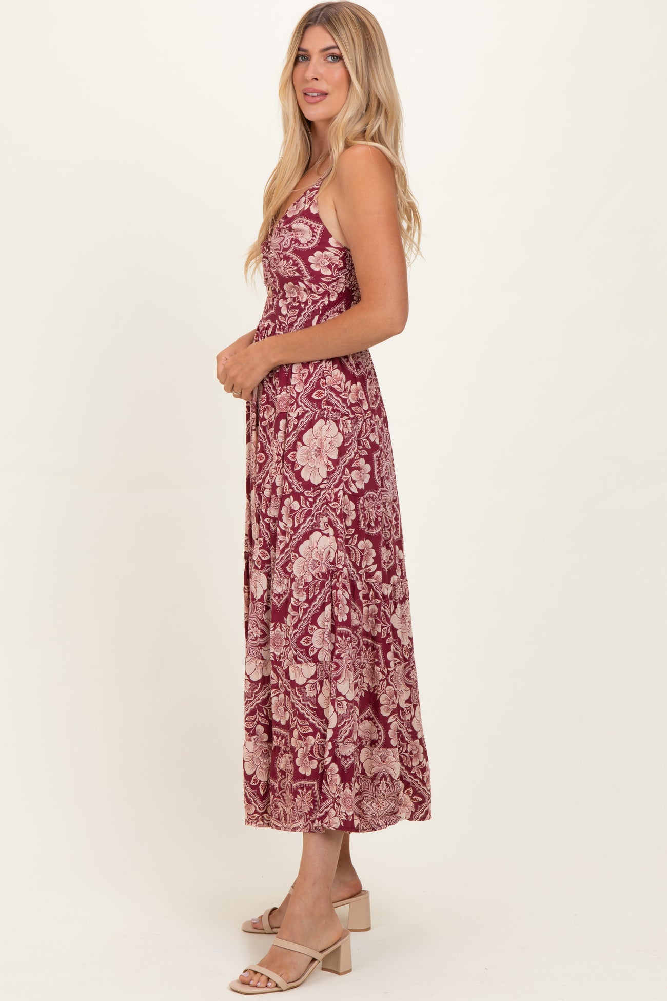 woman wearing a burgundy floral midi dress with a fitted bodice and flowy skirt, styled with nude block-heeled sandals
