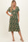 woman wearing a green floral print midi dress with a twist front and short sleeves, standing in a neutral background