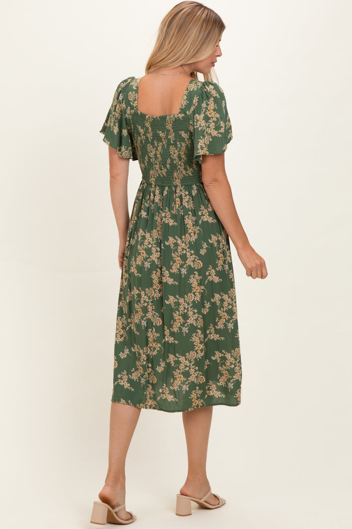 woman wearing a green floral midi dress with short flutter sleeves and a smocked back, shown from the back