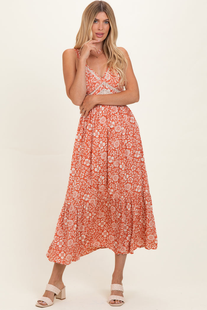 woman wearing an orange floral midi dress with spaghetti straps and a tiered skirt