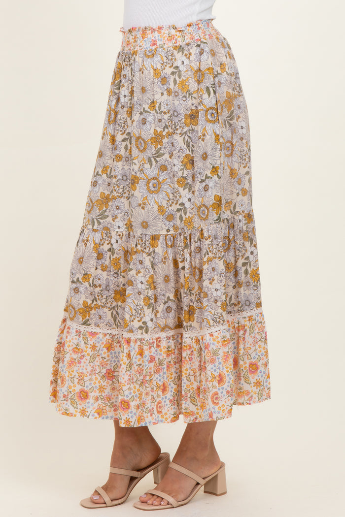 woman wearing a floral print maxi skirt with tiers in shades of yellow, orange, and white