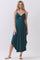 woman wearing a teal sleeveless maxi dress with a front twist detail and uneven hemline