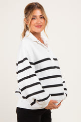 woman wearing a white and black striped maternity sweatshirt with a button collar and holding her baby bump