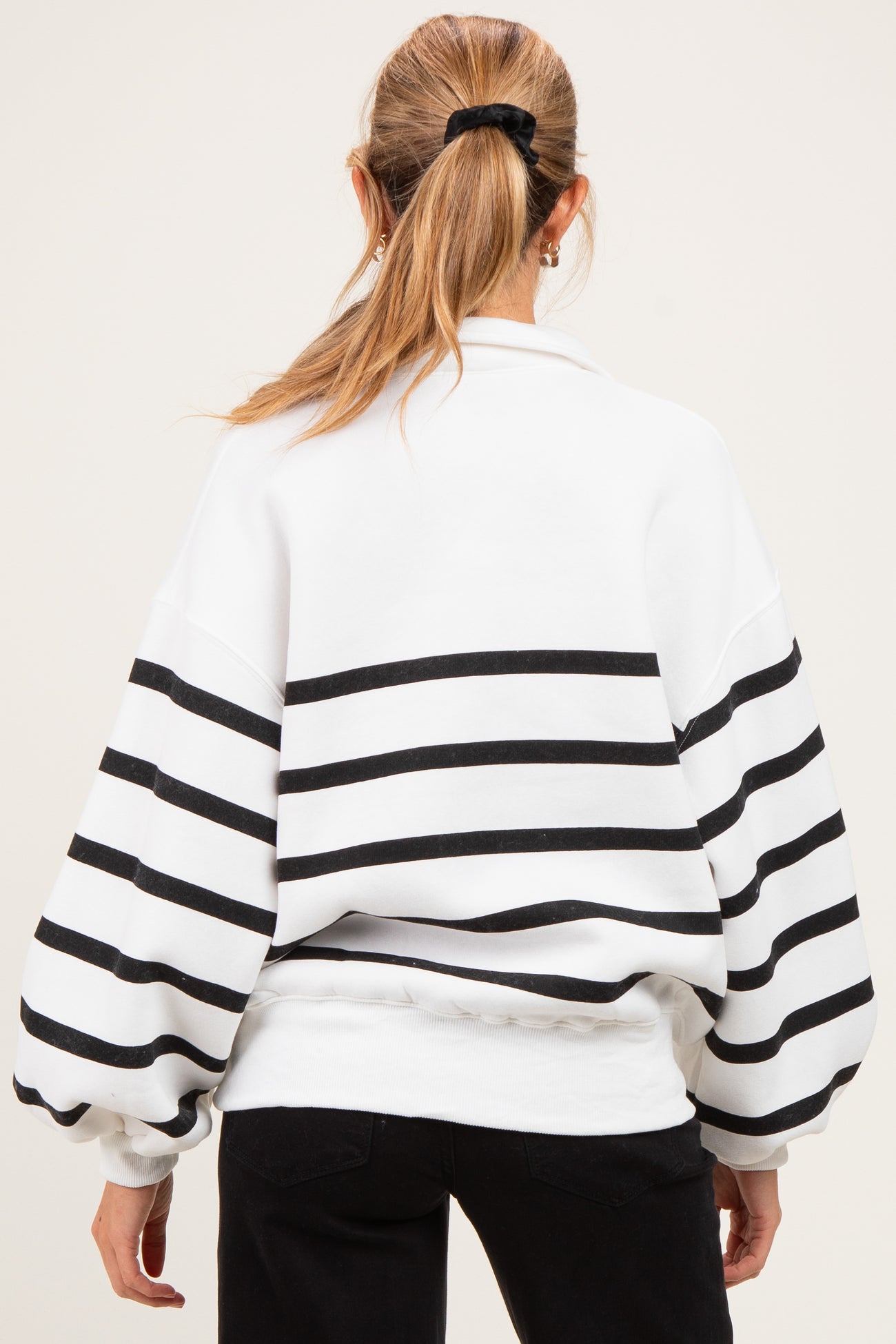 woman wearing a white and black striped maternity sweatshirt with a relaxed fit and balloon sleeves