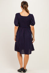 woman wearing a navy blue polka dot maternity dress with short puff sleeves and a smocked back design