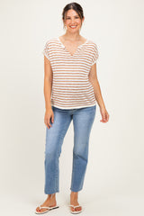 woman wearing a striped short sleeve maternity top in beige and rust with a v-neck, paired with light blue jeans