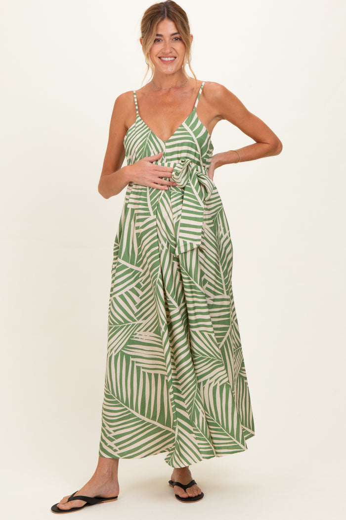 woman wearing a green and white striped maternity maxi dress with a tie waist and holding her baby bump