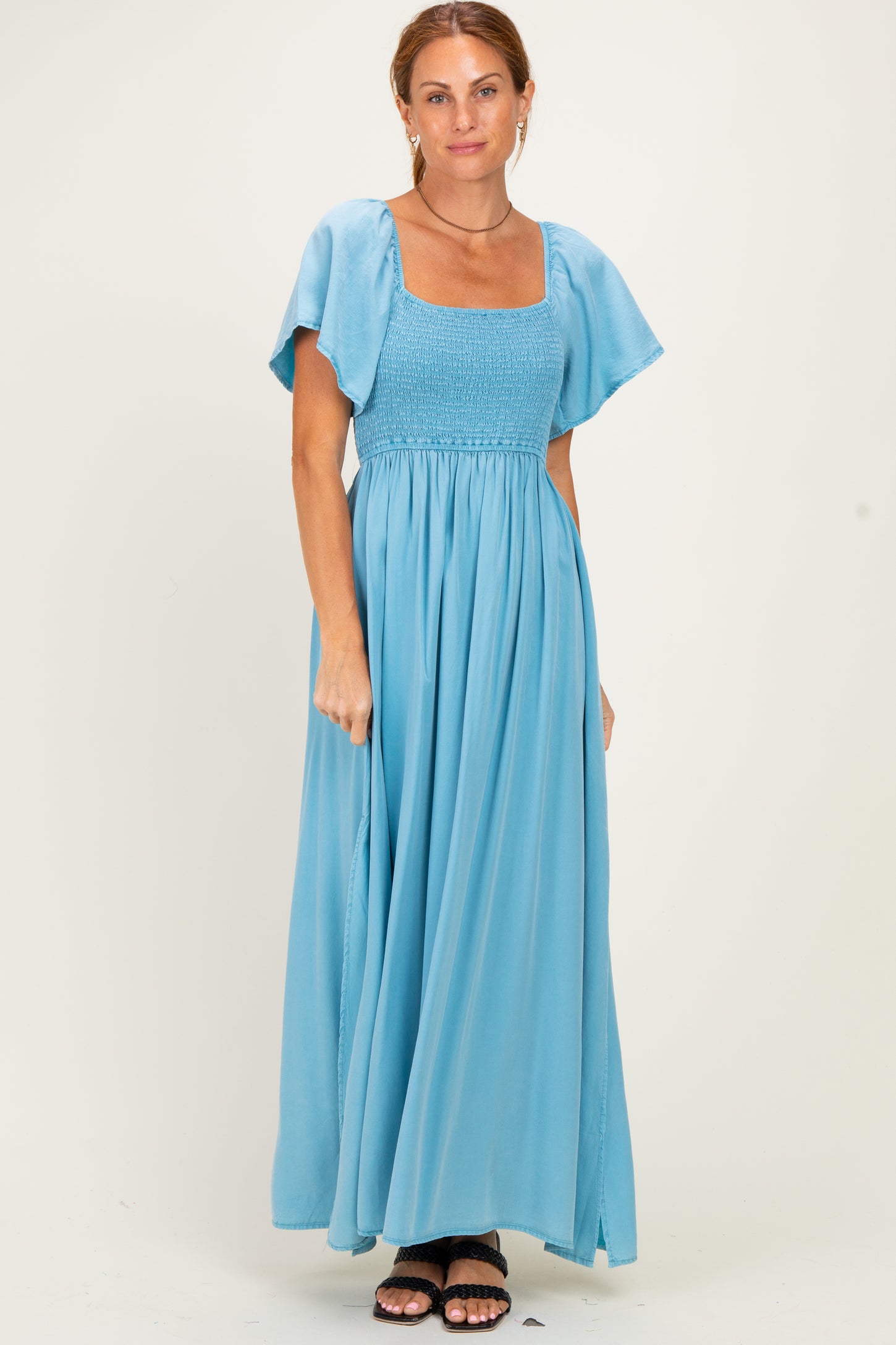 woman wearing a light blue maxi dress with a square neckline and flutter sleeves
