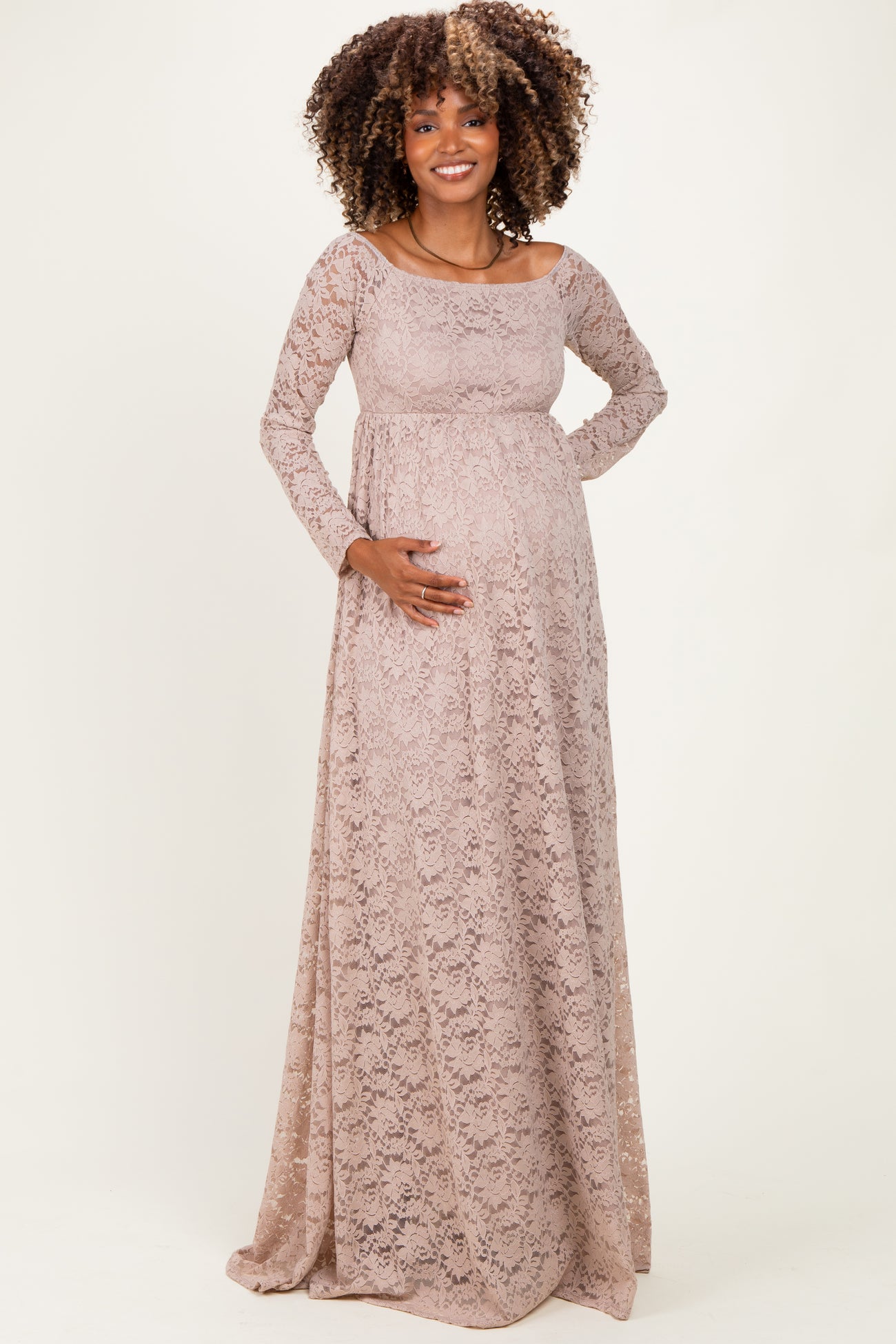 woman wearing a light pink lace maternity gown with long sleeves and a baby bump