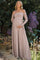 woman wearing a blush off-shoulder lace maternity gown, posing and holding her baby bump outdoors