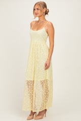 woman wearing a light yellow maxi dress with a sheer lace overlay and spaghetti straps