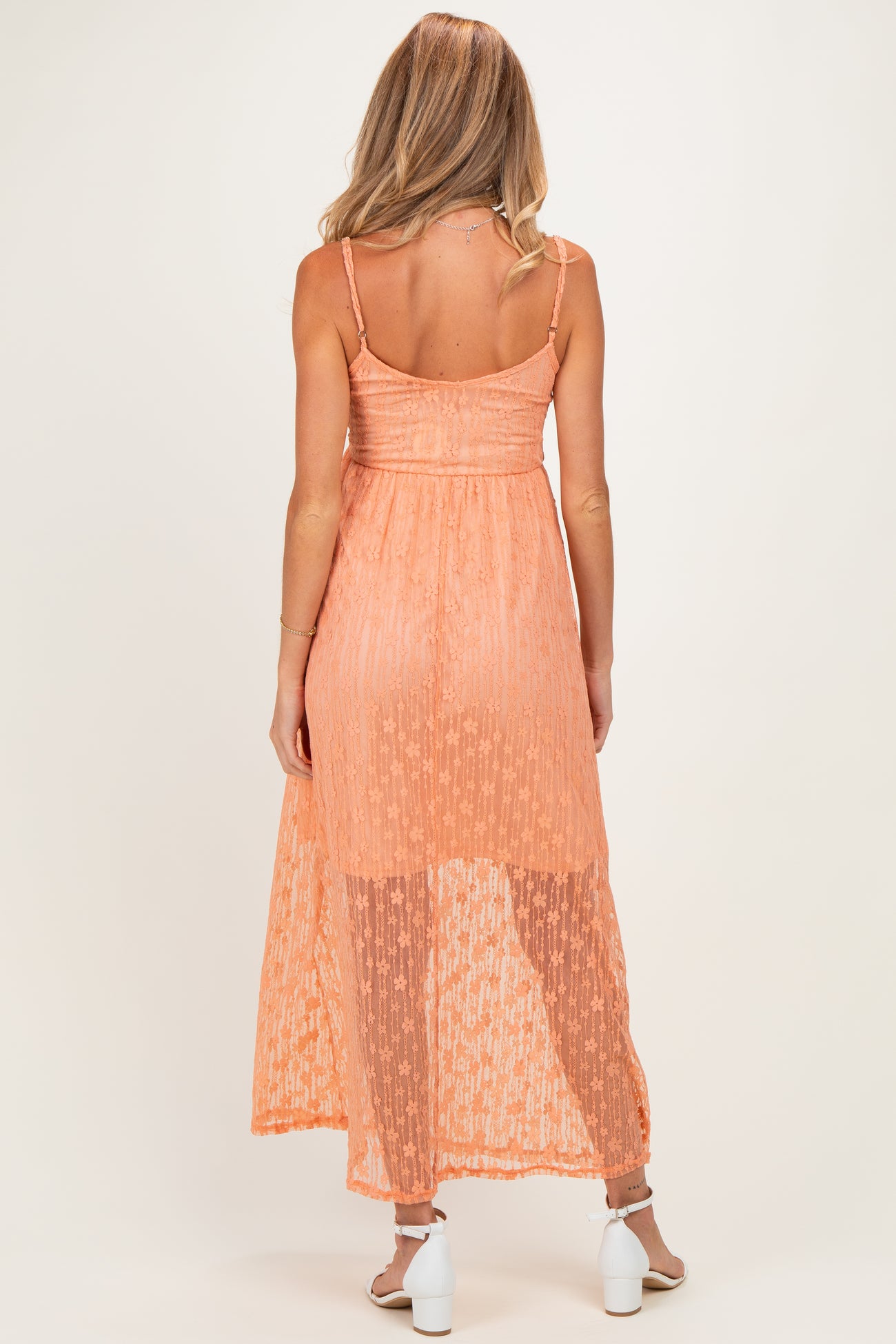 woman wearing a sheer orange maternity maxi dress with adjustable straps and a flowy silhouette