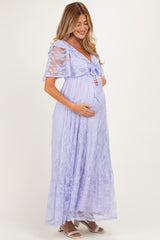 woman wearing a lavender lace maternity gown with a tie waist and short flutter sleeves, cradling her baby bump