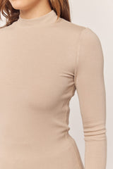 woman wearing a beige ribbed long sleeve mock neck top
