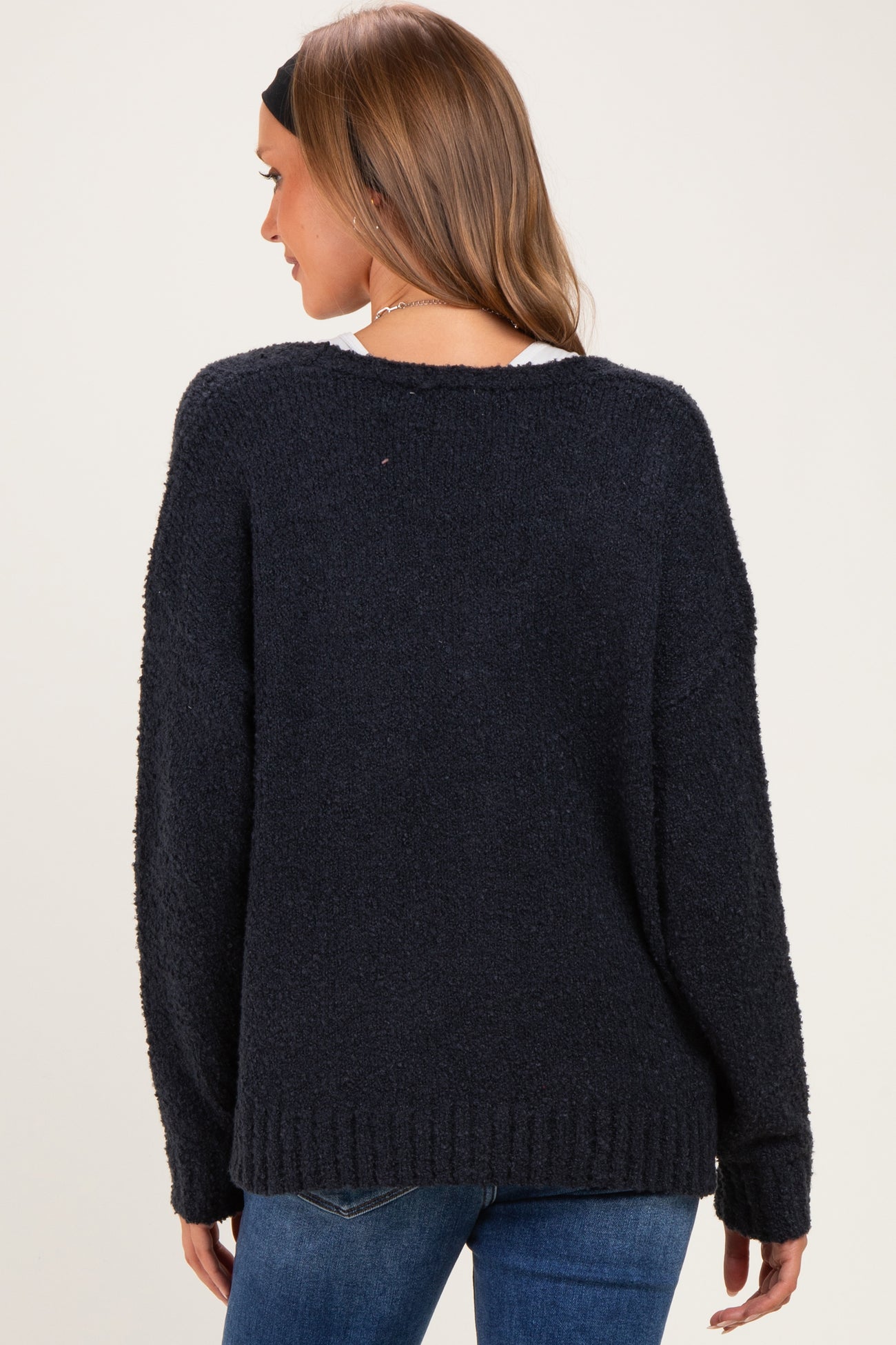 woman wearing a navy blue oversized maternity sweater, showing the back view, styled with a relaxed fit