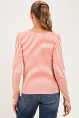 woman wearing a peach and white striped long sleeve maternity top, viewed from the back with dark jeans