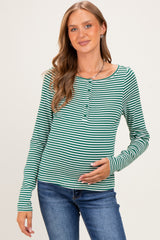 woman wearing a green and white striped long sleeve maternity top and holding her baby bump