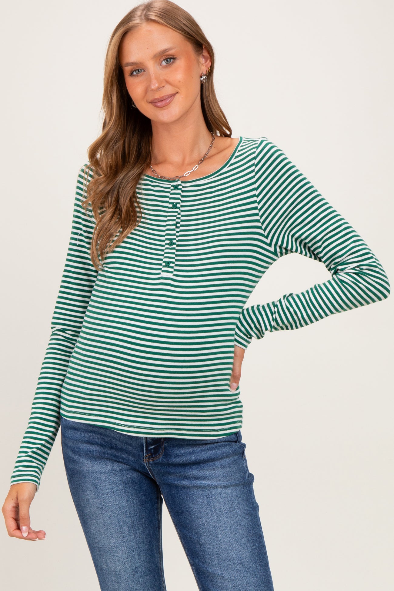 woman wearing a green and white striped maternity top with a button detail and long sleeves