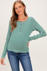 woman wearing a green and white striped maternity top with a button detail and long sleeves