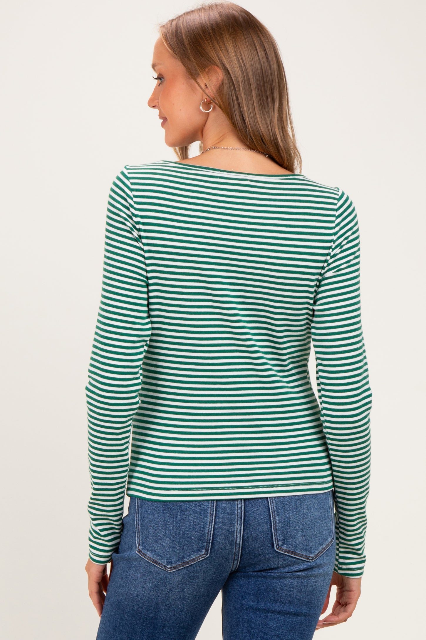 woman wearing a green and white striped long sleeve maternity top, viewed from the back