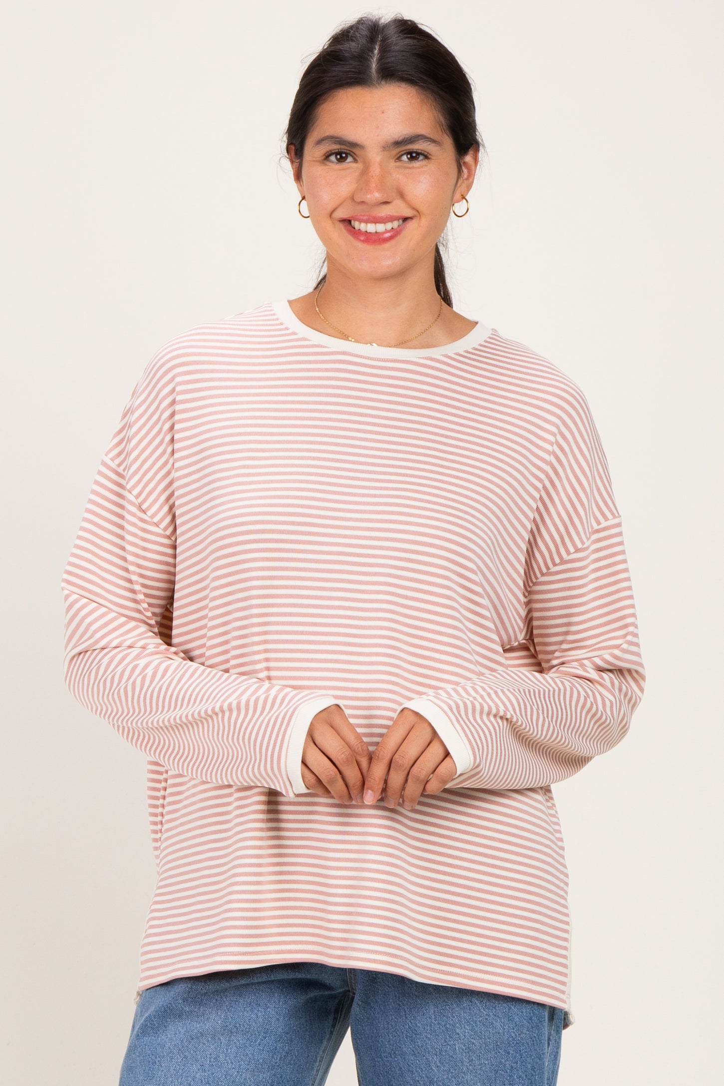 woman wearing a pink and white striped long sleeve top with a relaxed fit and a round neckline