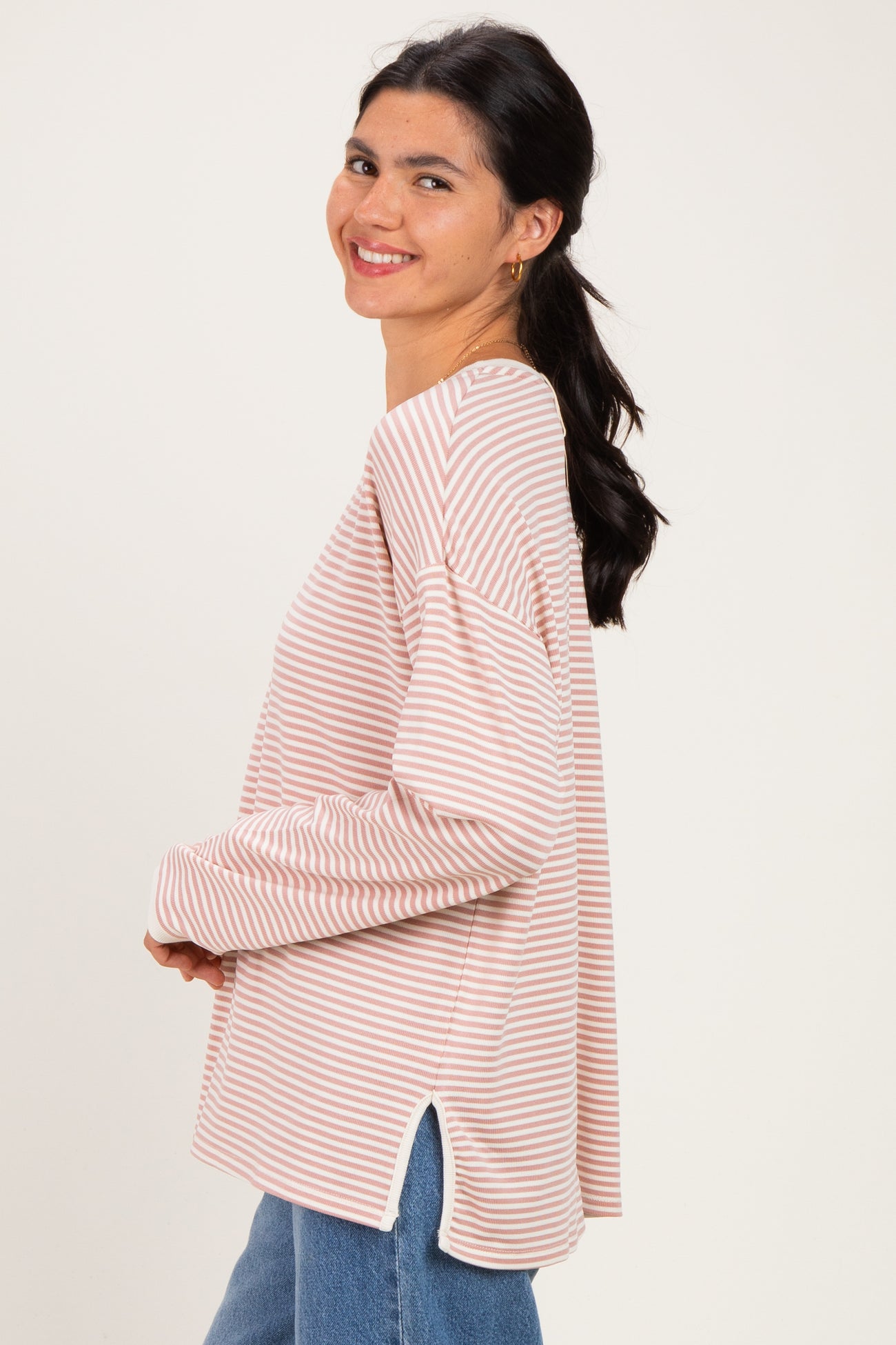 woman wearing a pink and white striped long sleeve top with side slits and relaxed fit