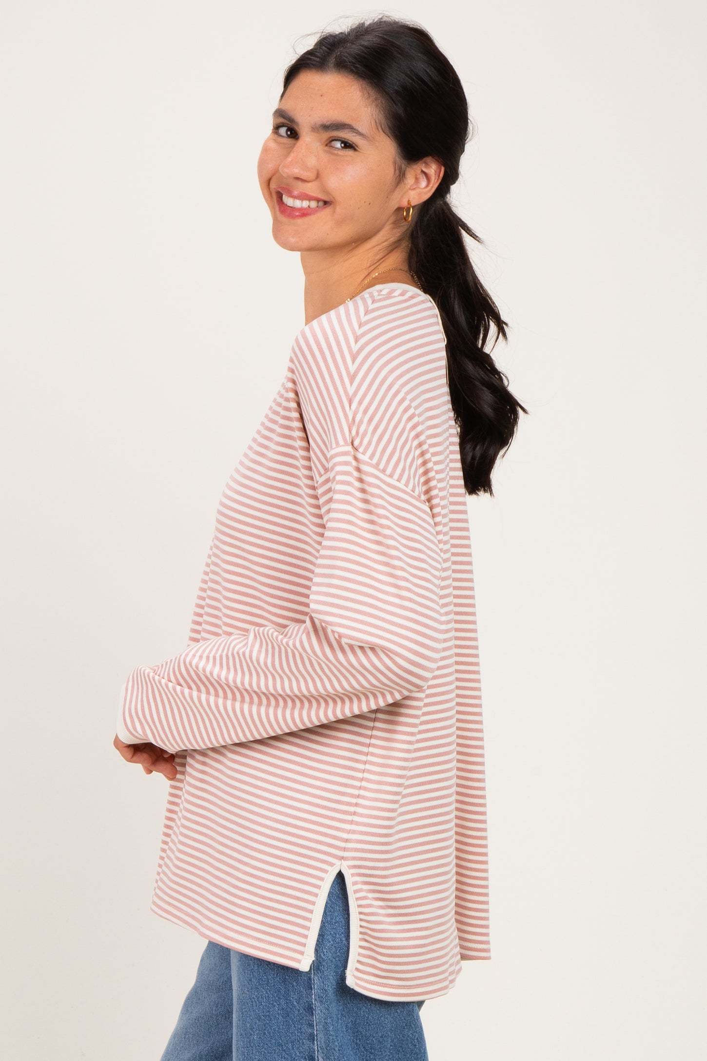 woman wearing a pink and white striped long sleeve top with side slits and relaxed fit