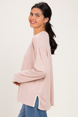woman wearing a pink and white striped long sleeve top with side slits and relaxed fit