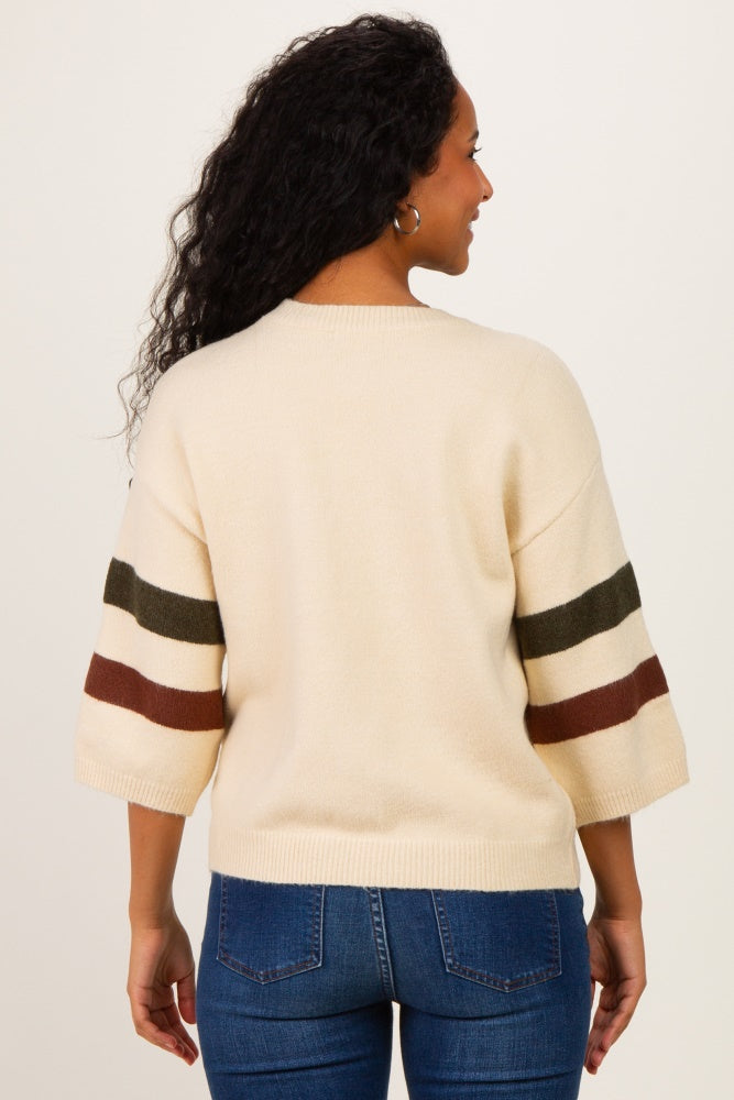 woman wearing a cream-colored maternity sweater with striped sleeves and a relaxed fit, showing her back