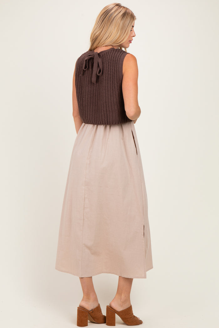 woman wearing a brown knitted top with a back tie and a beige midi skirt, standing with her back facing the camera