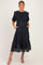 woman wearing a navy blue floral maternity dress with puff sleeves and pockets, showcasing her baby bump