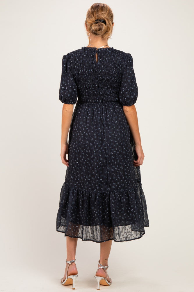woman wearing a navy blue floral midi maternity dress with puff sleeves and a tiered ruffle hem