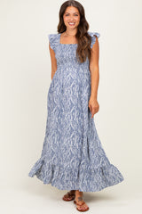 woman wearing a blue floral patterned maternity maxi dress with flutter sleeves and a smocked bodice