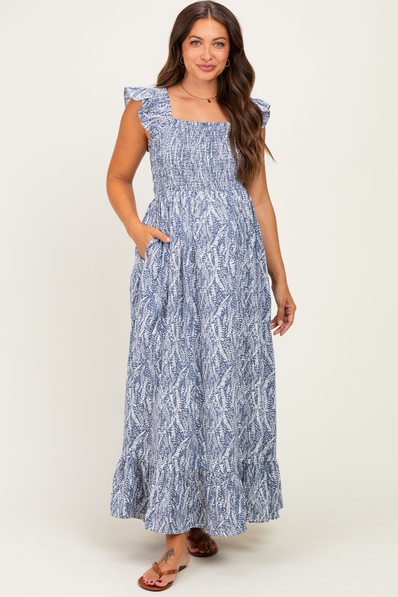 woman wearing a blue patterned maternity maxi dress with ruffle sleeves and pockets