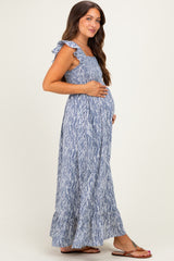 woman wearing a blue and white floral maternity maxi dress, holding her baby bump